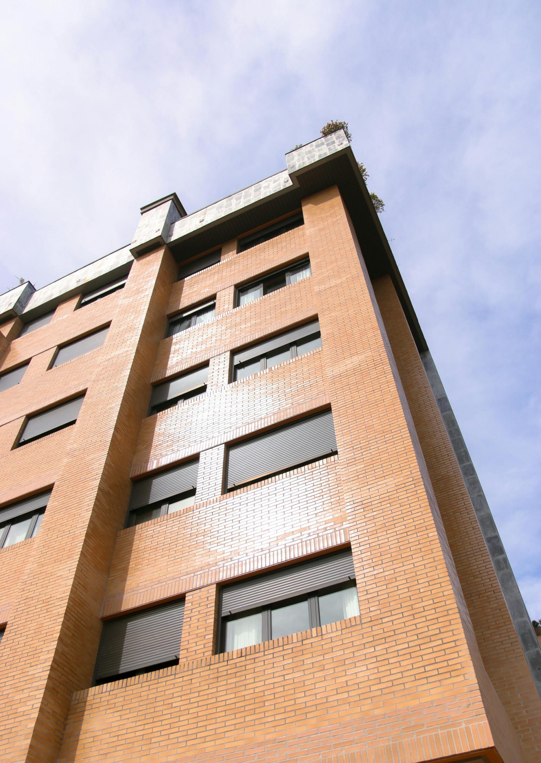 Low angle shot of a modern apartment building facade under clear skies in Oviedo, Spain.