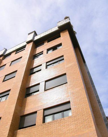 Low angle shot of a modern apartment building facade under clear skies in Oviedo, Spain.